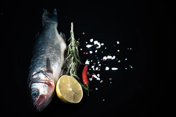 Fresh sea fish lying on dark background with spices. Space for t — Stock Photo, Image