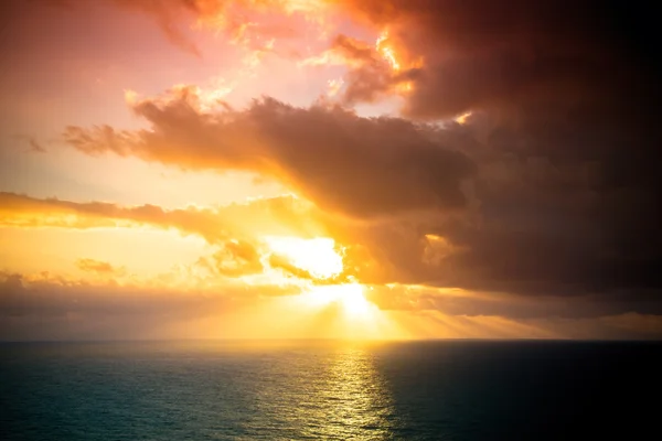 Dramatic sunset rays through a cloudy dark sky over the ocean. T — Stock Photo, Image