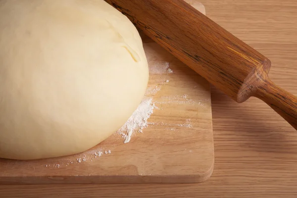 dough on a board and rolling pin with flour dusting. Close-up