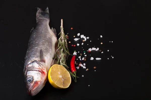 Pesce di mare fresco sdraiato su sfondo scuro con spezie. Spazio per t — Foto Stock