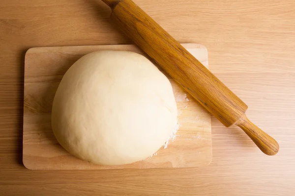 Dough on a board and rolling pin with flour for sprinkling — Stock Photo, Image