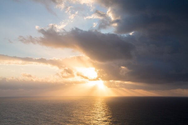 Драматические лучи заката сквозь туманное темное небо над океаном. T
