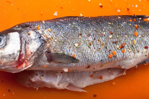 Fish and spices on a plastic cutting board. Fish in the process — Stock Photo, Image