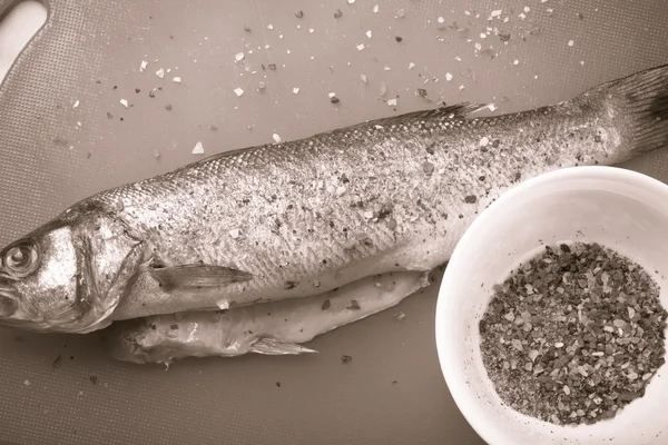 Fish and spices on a plastic cutting board. Fish in the process — Stock Photo, Image