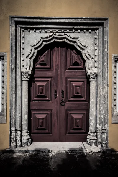 Puerta de madera vieja enmarcada por una piedra tallada. teñido — Foto de Stock