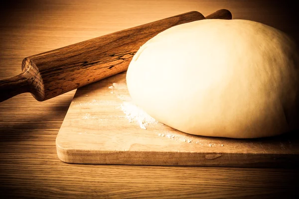 Rolling pin and dough on a wooden table. slightly tinted — Stock Photo, Image