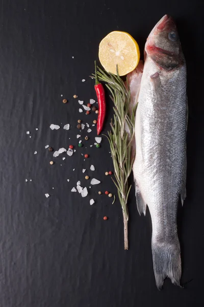 Frischer Fisch, Zitrone, Pfeffer und Rosmarin auf schwarzem Hintergrund. ti — Stockfoto