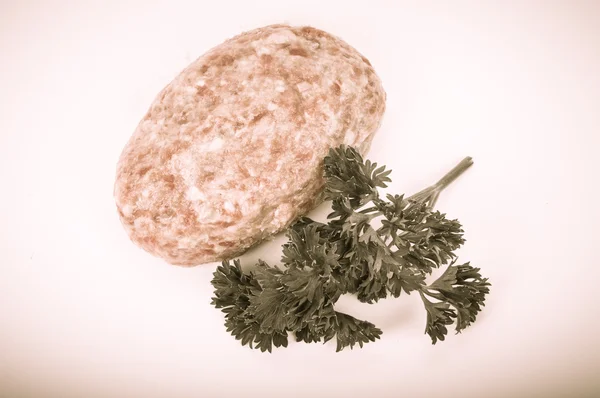 Raw meat cutlet with a sprig of parsley on a white background. T — Stock Photo, Image