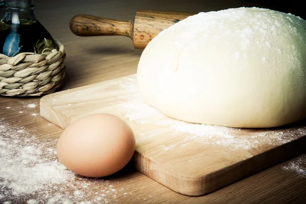 Dough on a board with flour. olive oil, eggs, rolling pin — Stock Photo, Image