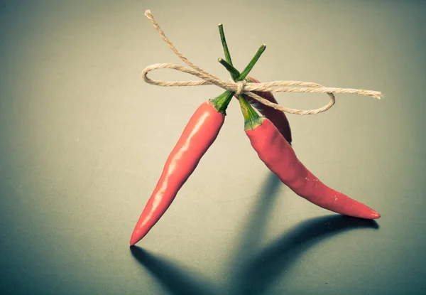 Red hot chili peppers gebonden bindgaren tegen donkere achtergrond — Stockfoto