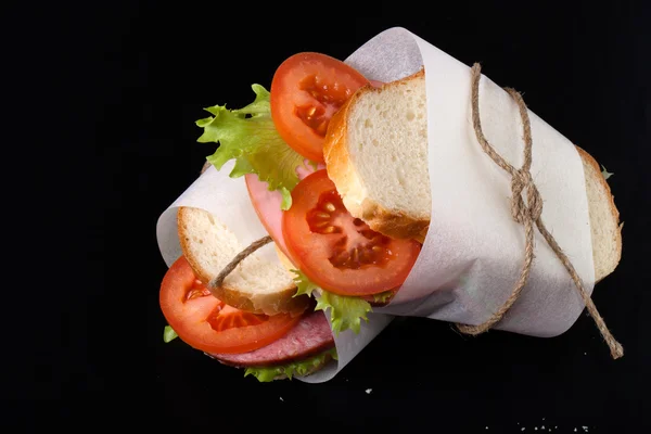Sandwich with sausage bandaged twine on a black background. With — Stock Photo, Image