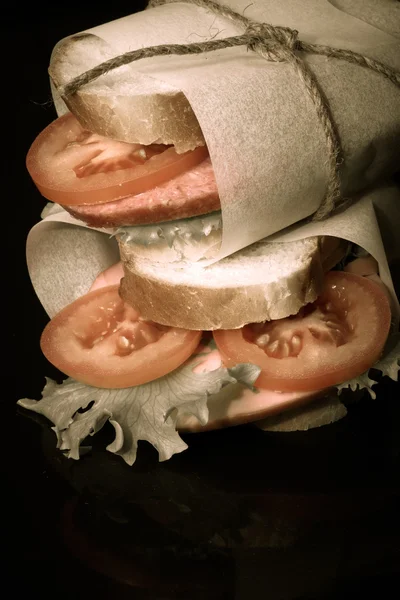 Sandwich avec ficelle pansée à la saucisse sur fond noir . — Photo