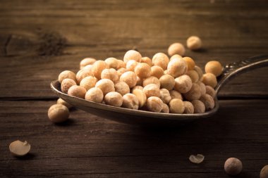 ahşap bir masa üzerinde bir gümüş kaşık kuru bezelye. renkli
