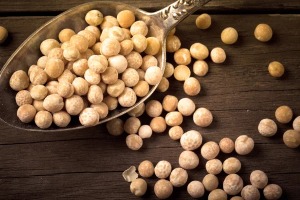 Dry peas in a silver spoon on a wooden table. tinted — Stock Photo, Image