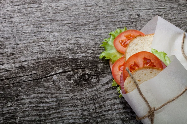 Sandwich bandaged twine on a textured wooden board. — Stock Photo, Image