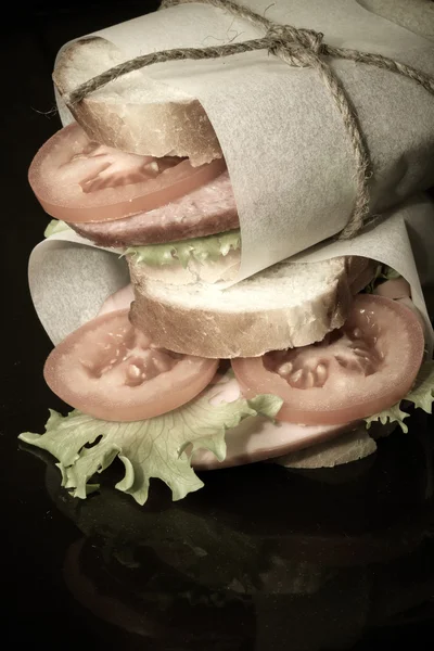 Sandwich avec ficelle pansée à la saucisse sur fond noir . — Photo