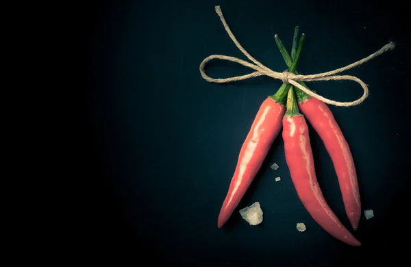 Verwante hot rode chili peppers en een groot kristal zout op een donker — Stockfoto