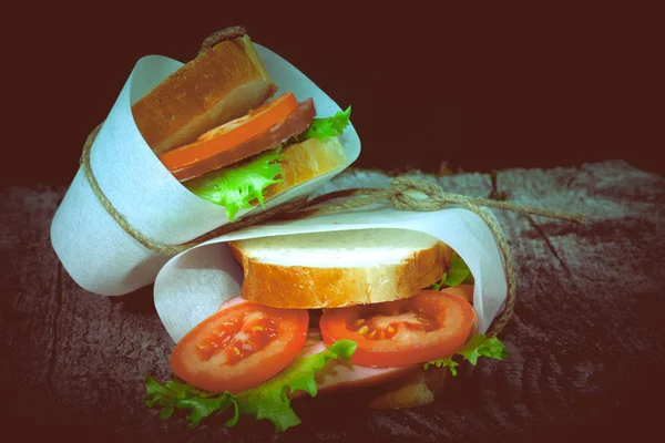 Sandwich bandaged twine on a textured wooden board. tinted.old f — Stock Photo, Image