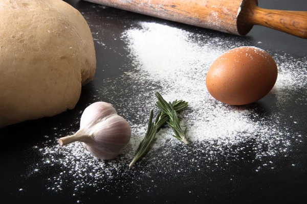 Flour, rolling pin, egg, rosemary, garlic and dough for pie — Stock Photo, Image