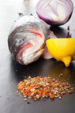 Çiğ balık, soğan, limon ve baharat siyah bir tablo