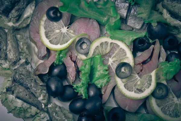 Surtido de pescado, arenque, rodajas de limón y aceitunas. Tonificado — Foto de Stock