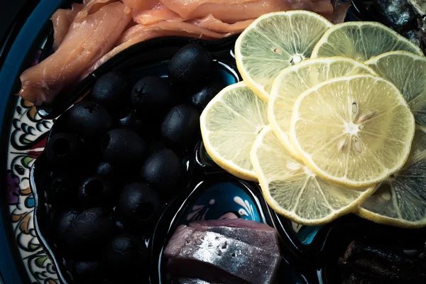 Ассортимент рыбы, оливок, лимонных ломтиков на восточном блюде. Toned — стоковое фото