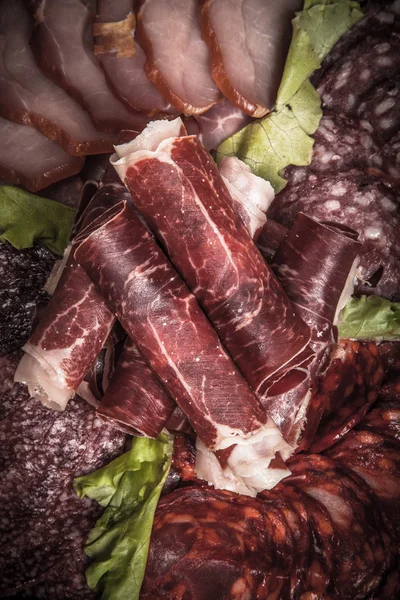 Slices of different kinds of meat with green salad. Toned — Stock Photo, Image