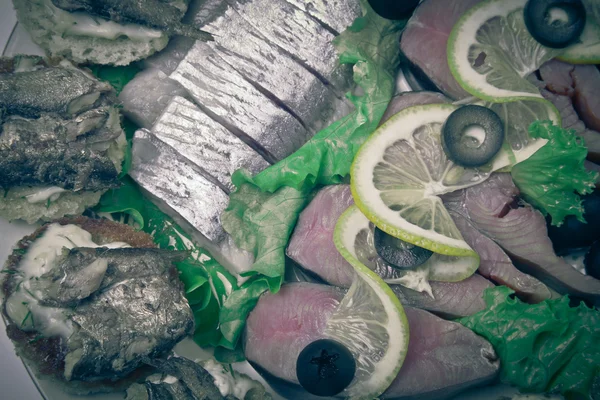 Assorty of fish, herring, lemon slices and olives. Toned — Stock Photo, Image