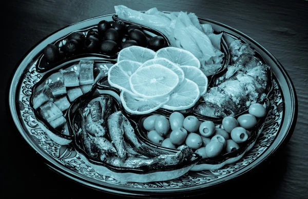 Assorty of fish, olives, lemon slices on oriental dish. Toned — Stock Photo, Image