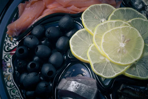 Ассортимент рыбы, оливок, лимонных ломтиков на восточном блюде. Toned — стоковое фото