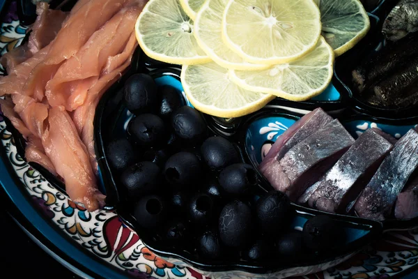 Assorty of fish, olives, lemon slices on oriental dish. Toned — Stock Photo, Image