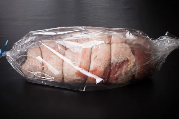 Сырое мясо с веревкой в упаковке на черном фоне — стоковое фото