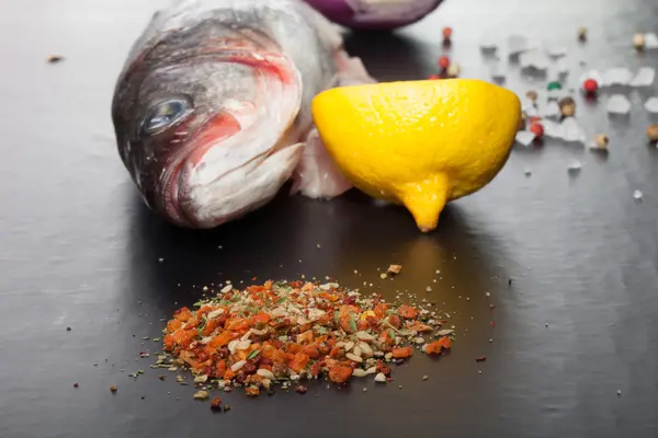 Nyers hal, hagyma, citrom és fűszerek a fekete asztal — Stock Fotó