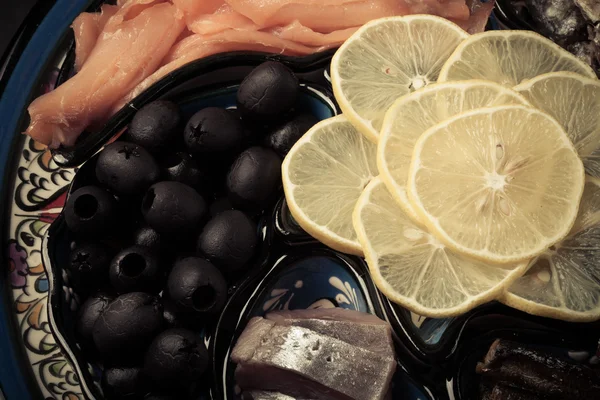 Assorty of fish, olives, lemon slices on oriental dish. Toned — Stock Photo, Image