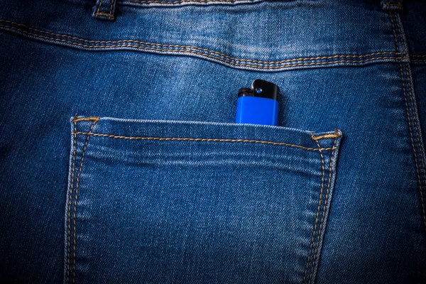 The pocket of jeans with lighter. Cloth background. Toned — Stock Photo, Image