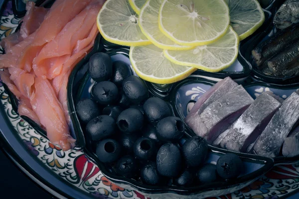 Assorty of fish, olives, lemon slices on oriental dish. Toned — Stock Photo, Image