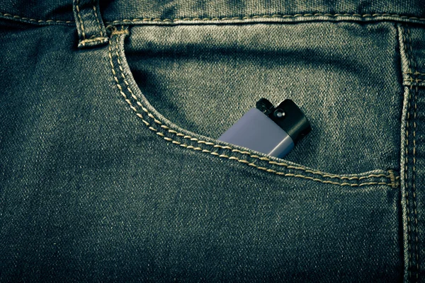 De zak van jeans met lichter. Doek achtergrond. Afgezwakt — Stockfoto