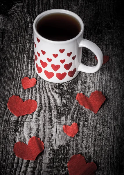 Valentinsherzen und eine Tasse Tee auf dem alten Holztisch. gemildert — Stockfoto