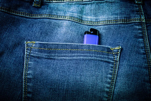 O bolso de jeans com isqueiro. Fundo de pano. Tonificado — Fotografia de Stock