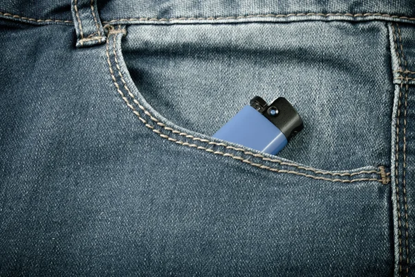 The pocket of jeans with lighter. Cloth background. Toned — Stock Photo, Image