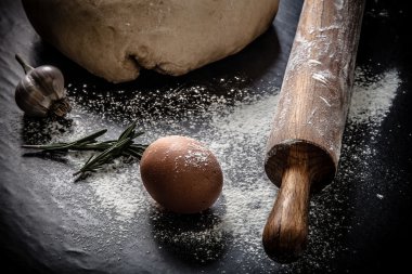 bir kara tahta un ile hamur. yumurta, oklava, sarımsak. Ti