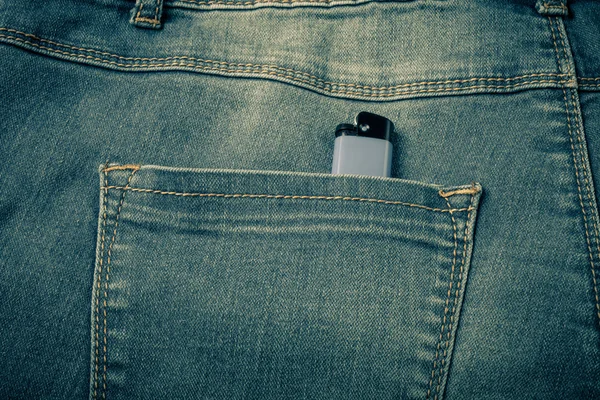 De zak van jeans met lichter. Doek achtergrond. Afgezwakt — Stockfoto