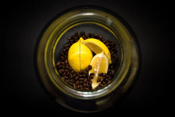 Лимон и кедровые орехи в стеклянной банке на черном фоне — стоковое фото
