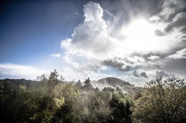 Güneşin dağların üzerinden bulutlarda. Tonda
