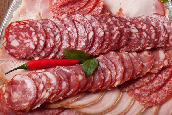 Plate with different kinds of sliced sausage and red hot chilli — Stock Photo, Image