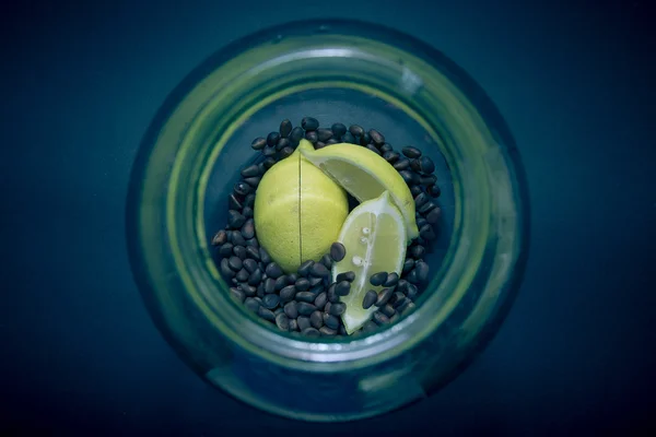 Limão e pinhões em um jarro de vidro em um fundo preto. Tonificado — Fotografia de Stock