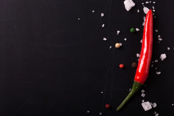 Red hot chilli pepper with sea salt and colored pepper on black — Stock Photo, Image