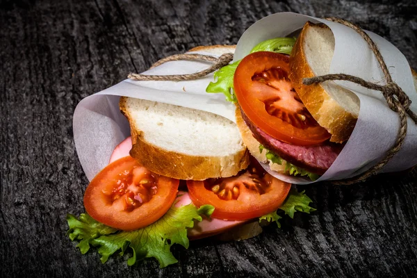 Sandwich zawiązał sznurka na teksturowane deska. Stonowanych — Zdjęcie stockowe