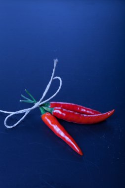 Eski siyah arka plan üzerine ip ile üç kırmızı sıcak biber biber. T