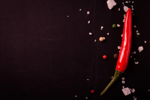 Red hot chilli pepper with sea salt and colored pepper on black — Stock Photo, Image